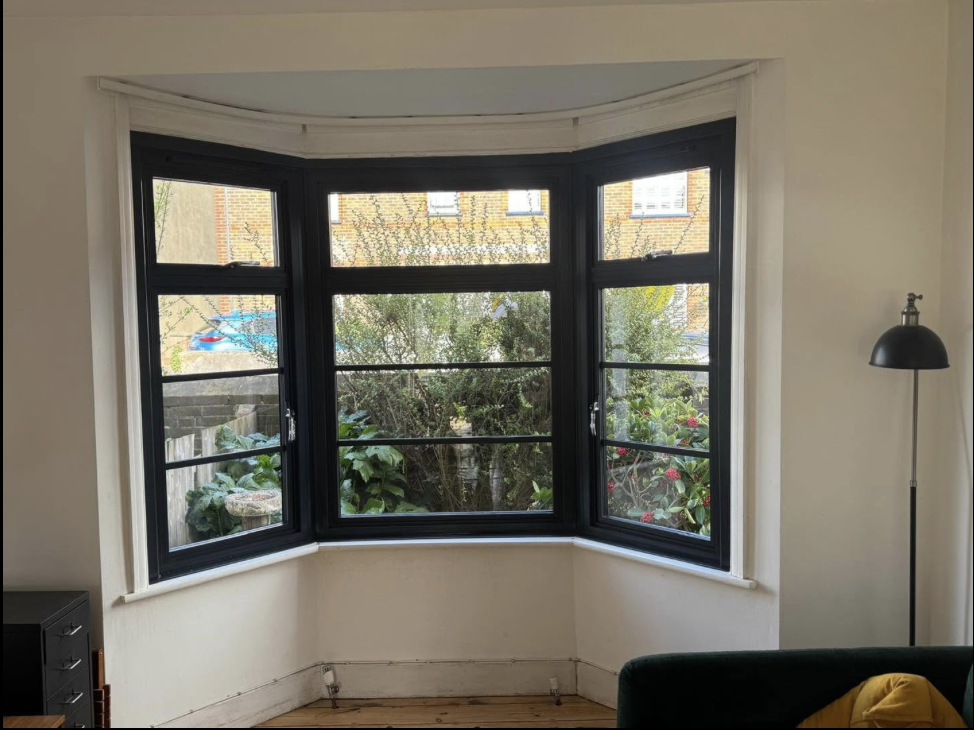 Black framed bay window seen from inside a living room