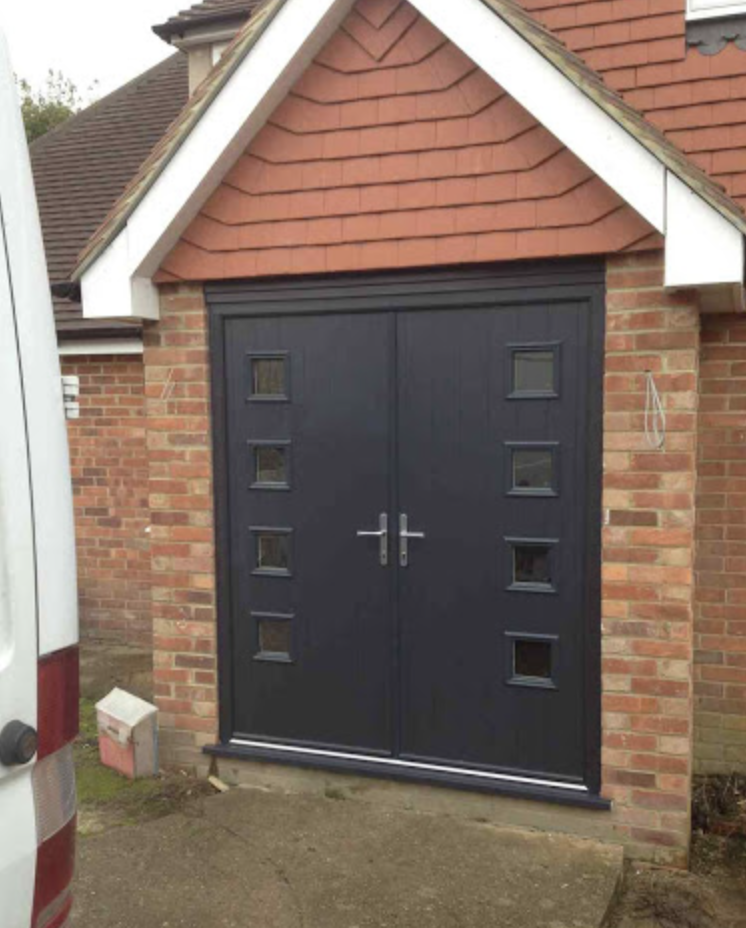 Anthracite grey double composite doors fitted under a tiled porch