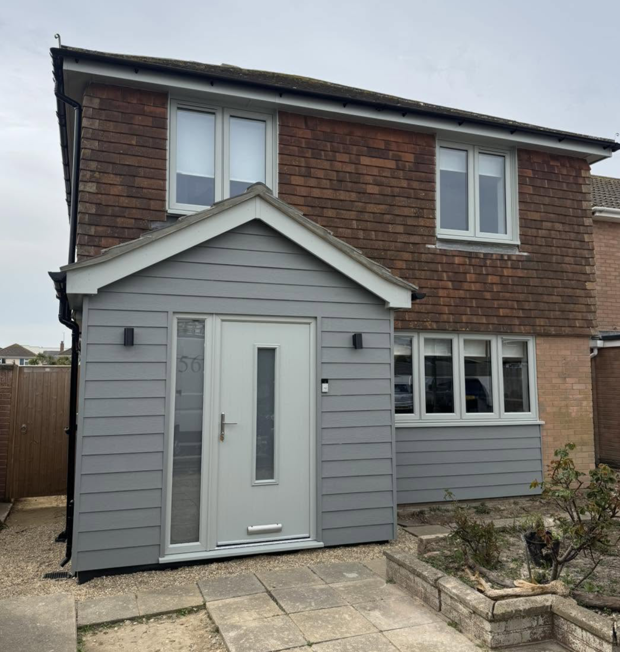 House with a new grey clad porch, white front door and black guttering