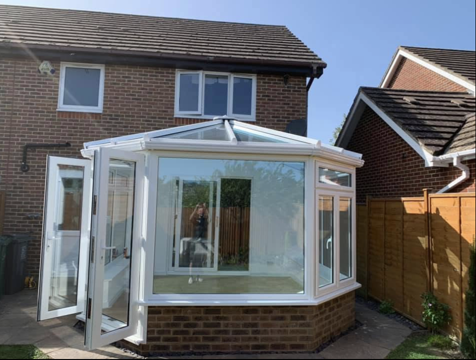 White uPVC conservatory with a glass roof and French doors on a brick house