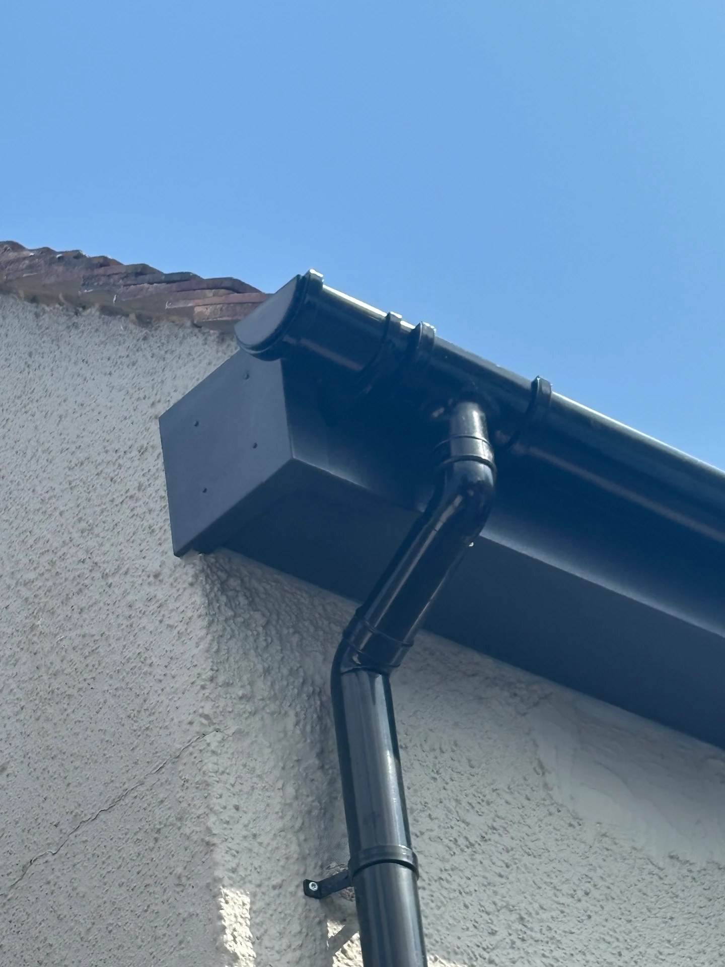 New black uPVC fascia, guttering and downpipe on a rendered house