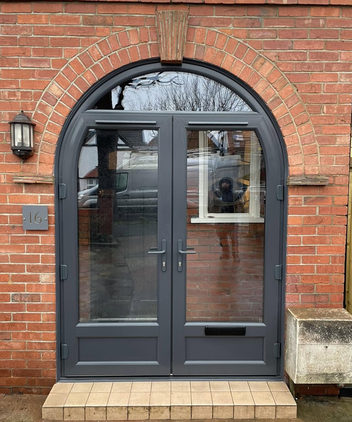 Anthracite grey arched French doors fitted into a red brick opening